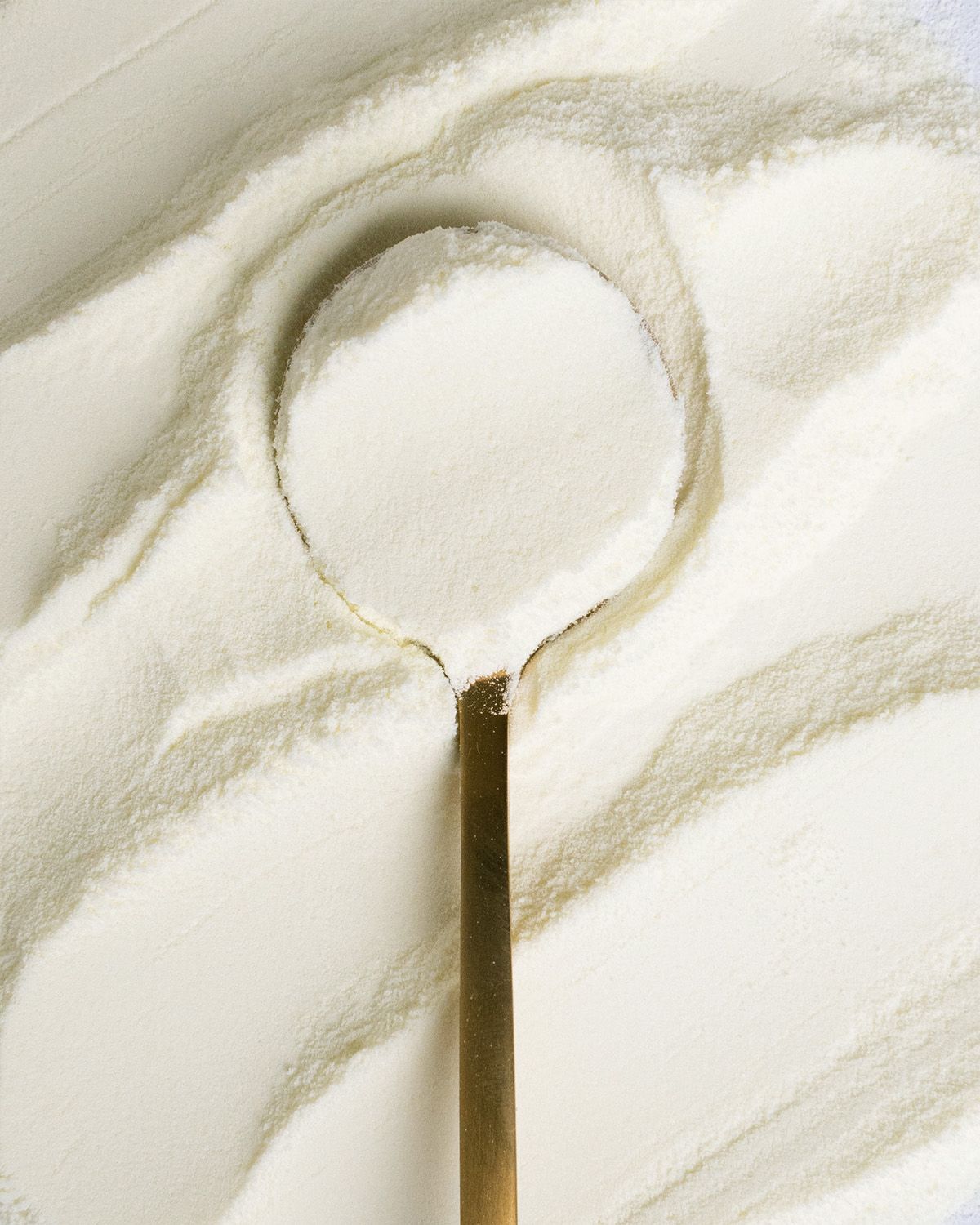 Ein Löffel mit Magermilchpulver auf einem Haufen Pulver.