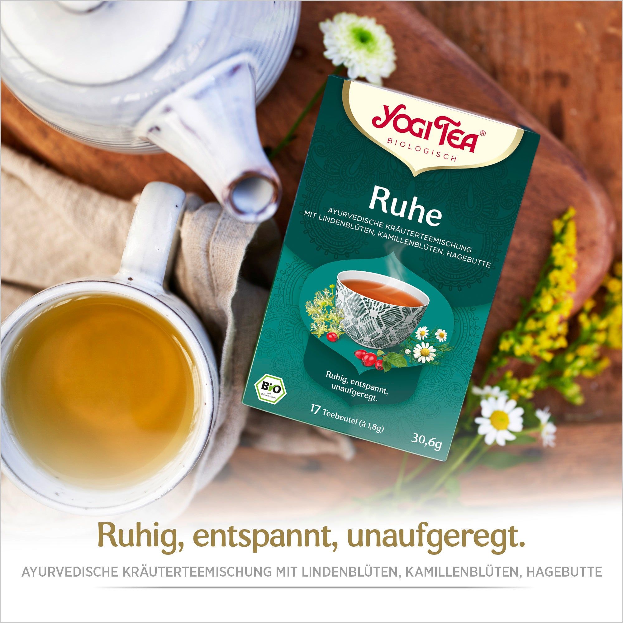 Yogi Tea Ruhe Packung neben Tasse Tee und Teekanne. Bio-Siegel sichtbar. Text: Ruhe, entspannt, unaufgeregt.