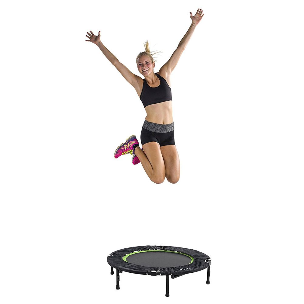 Frau springt jubelnd über Fitness Trampolin. Trampolin mit Haltebügel, schwarzer Bezug.