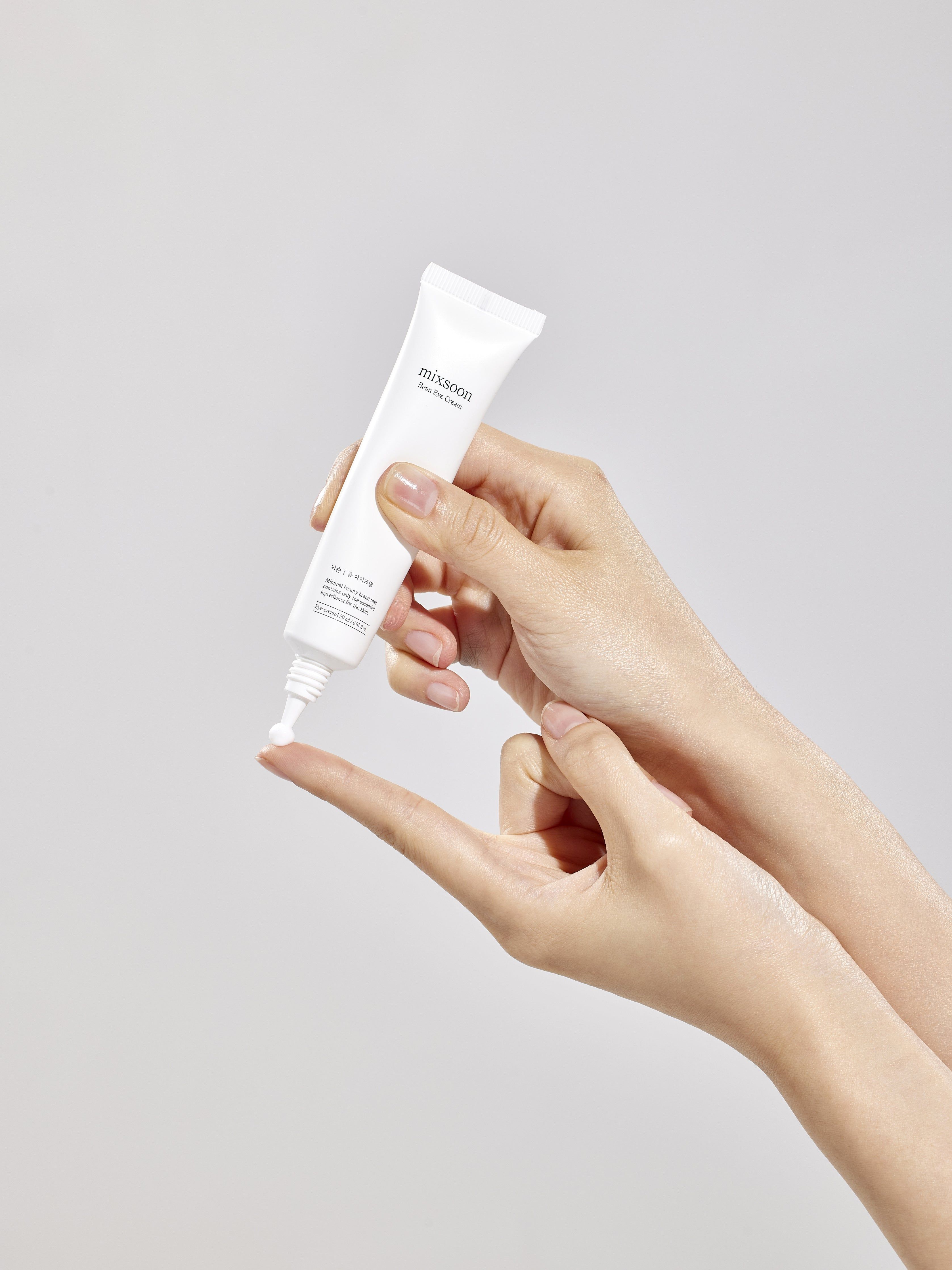 Hand gibt Mixsoon Bean Eye Cream auf Finger.