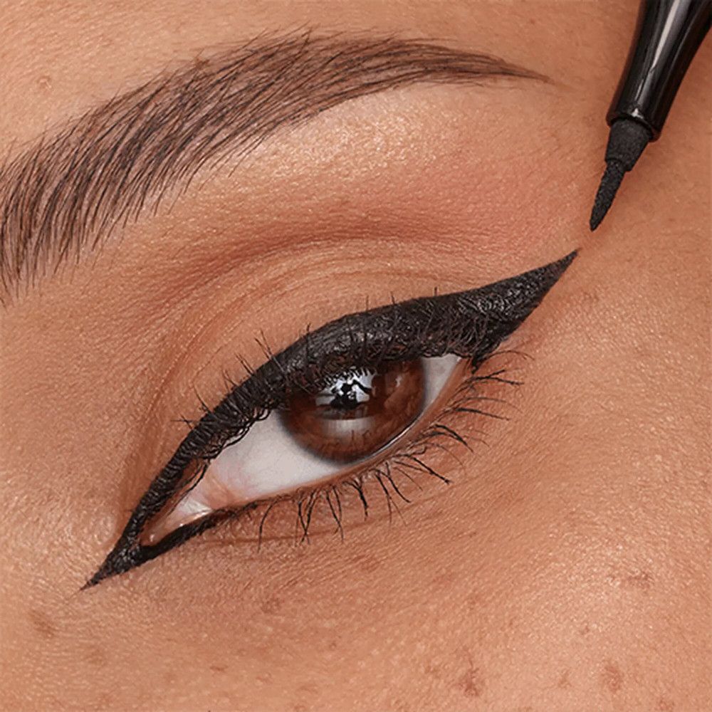 Nahaufnahme eines Auges mit aufgetragenem schwarzem Eyeliner. Der Eyeliner wird aufgetragen.