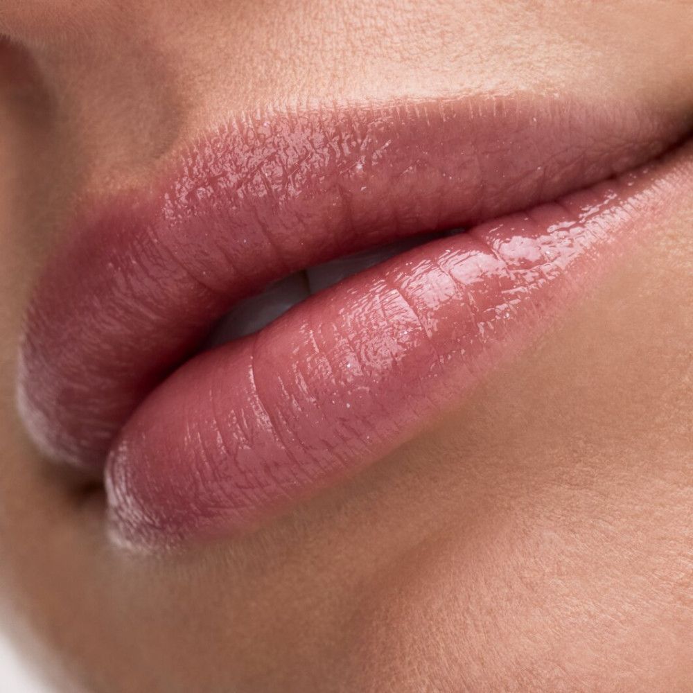 Nahaufnahme von Lippen mit aufgetragenem Lippenbalsam. Glänzendes Finish.