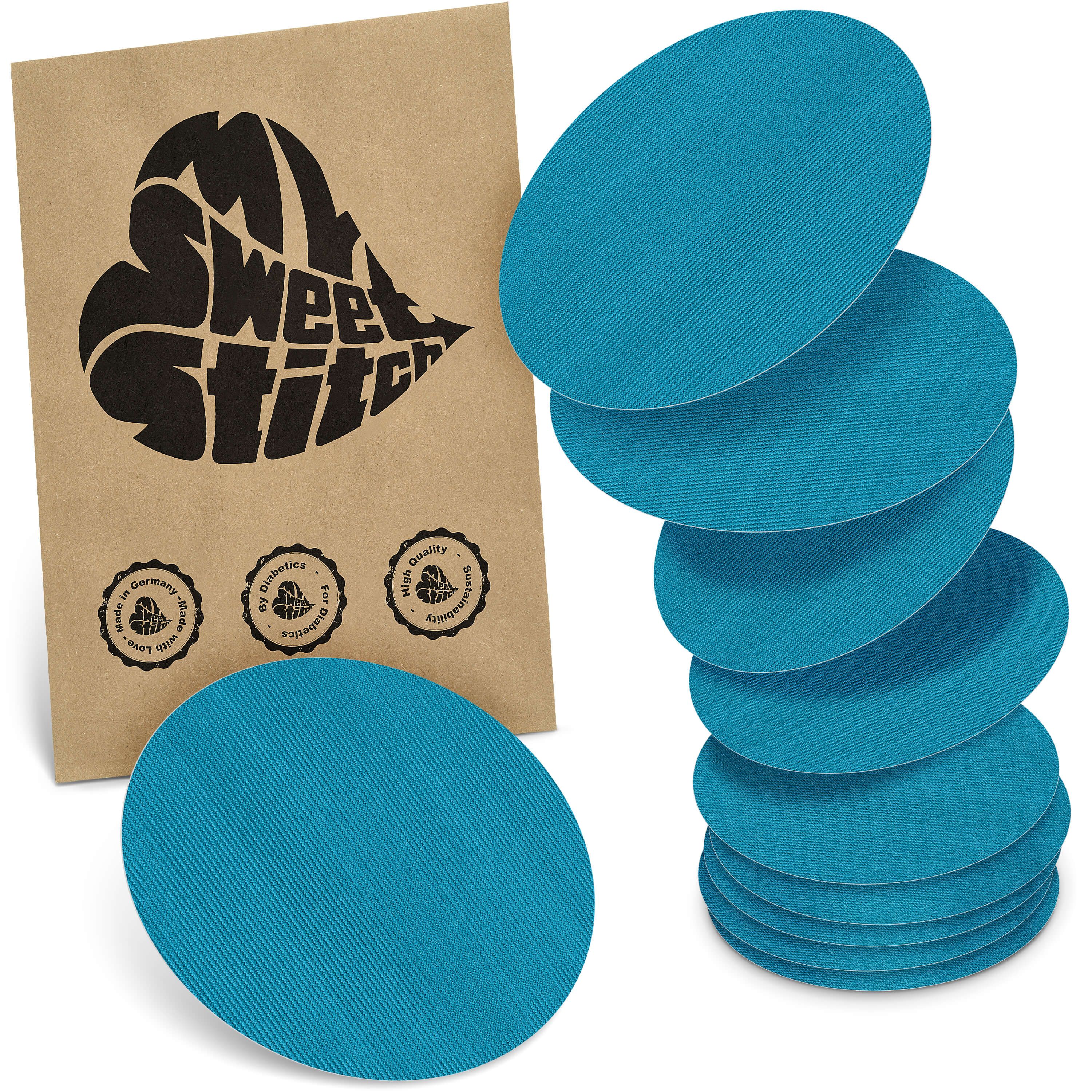 Blaue, ovale Pflaster. Verpackung mit Logo und Qualitätssiegeln. Mehrere Pflaster liegen gestapelt.