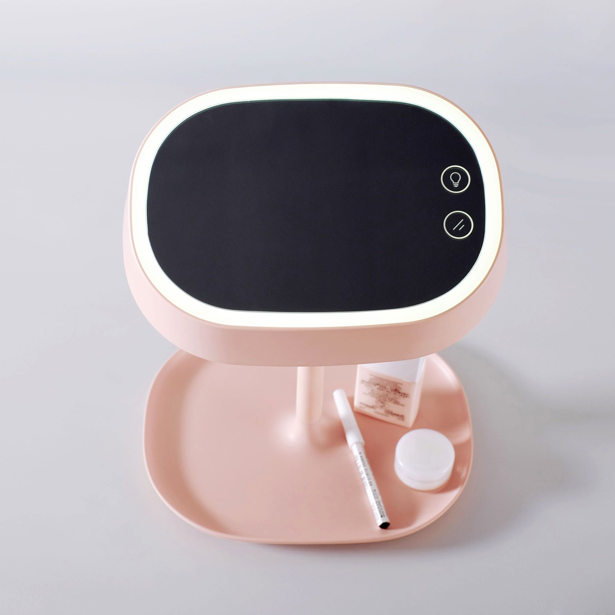 Rosa Lampe mit LED-Spiegel. Ovaler Spiegel mit Beleuchtung, zwei Knöpfen. Untere Ablage mit Kosmetikartikeln.