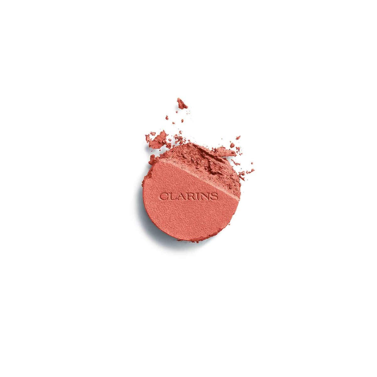 Clarins Joli Blush 07 Cheeky Peach. Zerbrochener, runder Blush-Kompaktpuder. Aufschrift Clarins. Pfirsichfarben.