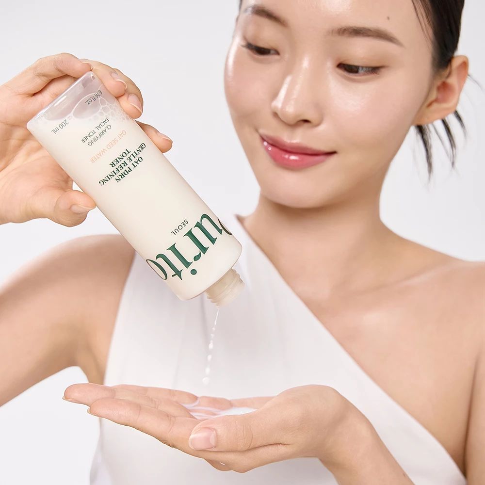 Frau gießt Toner aus einer Flasche in ihre Hand. Aufschrift: Purito, Oat PDRN Gentle Refining Toner.
