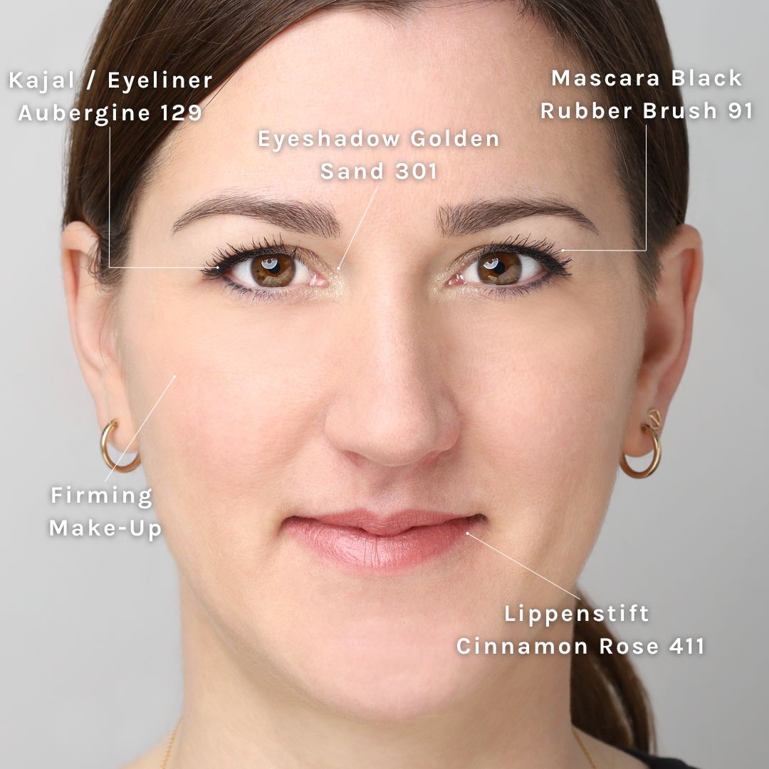 Gesicht mit Make-up. Kajal, Lidschatten, Lippenstift und Mascara. Alle Produkte sind beschriftet und auf dem Gesicht markiert.
