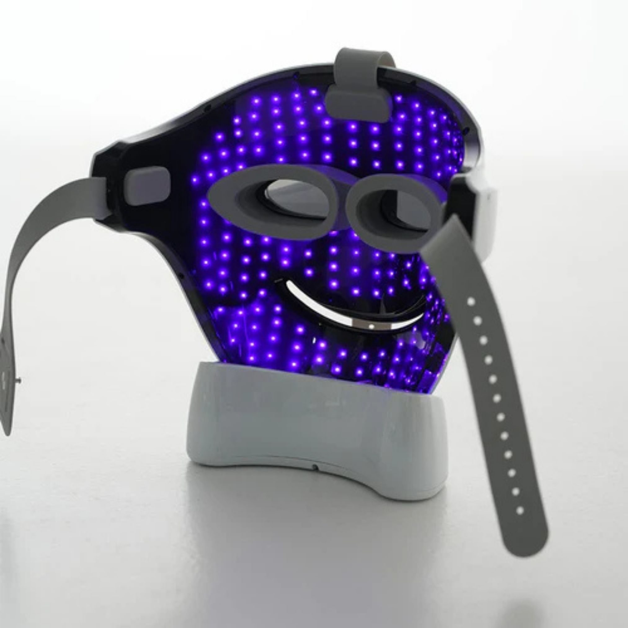Gesichtsmaske mit violetten LEDs. Graue Träger und Halterung. Maske auf weißer Basis.