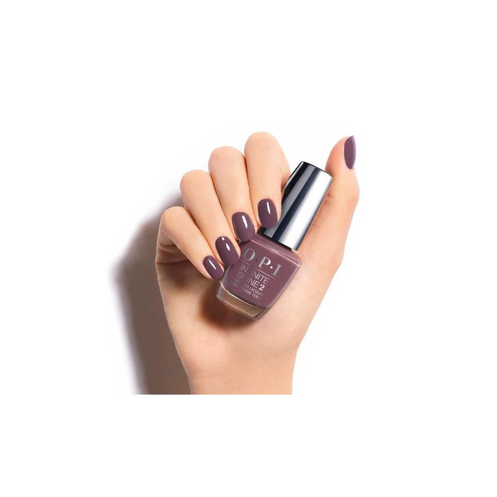 Hand mit lackierten Nägeln und Nagellackflasche. Flasche mit silbernem Deckel, Produktname OPI Infinite Shine 2.