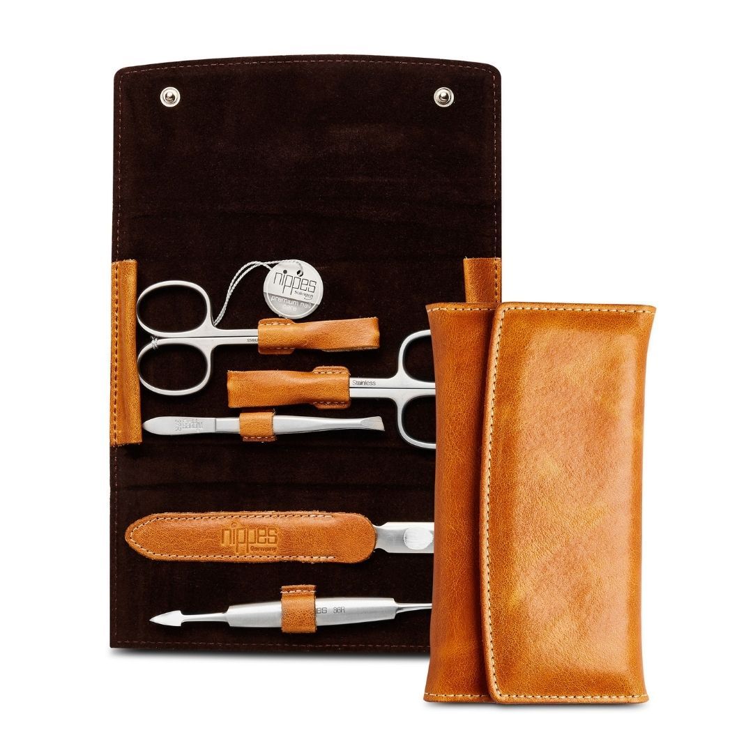 Maniküre-Etui COGNAC, geöffnet. Enthält Schere, Nagelfeile und weitere Instrumente. Braunes Lederetui mit cognacfarbenen Details.