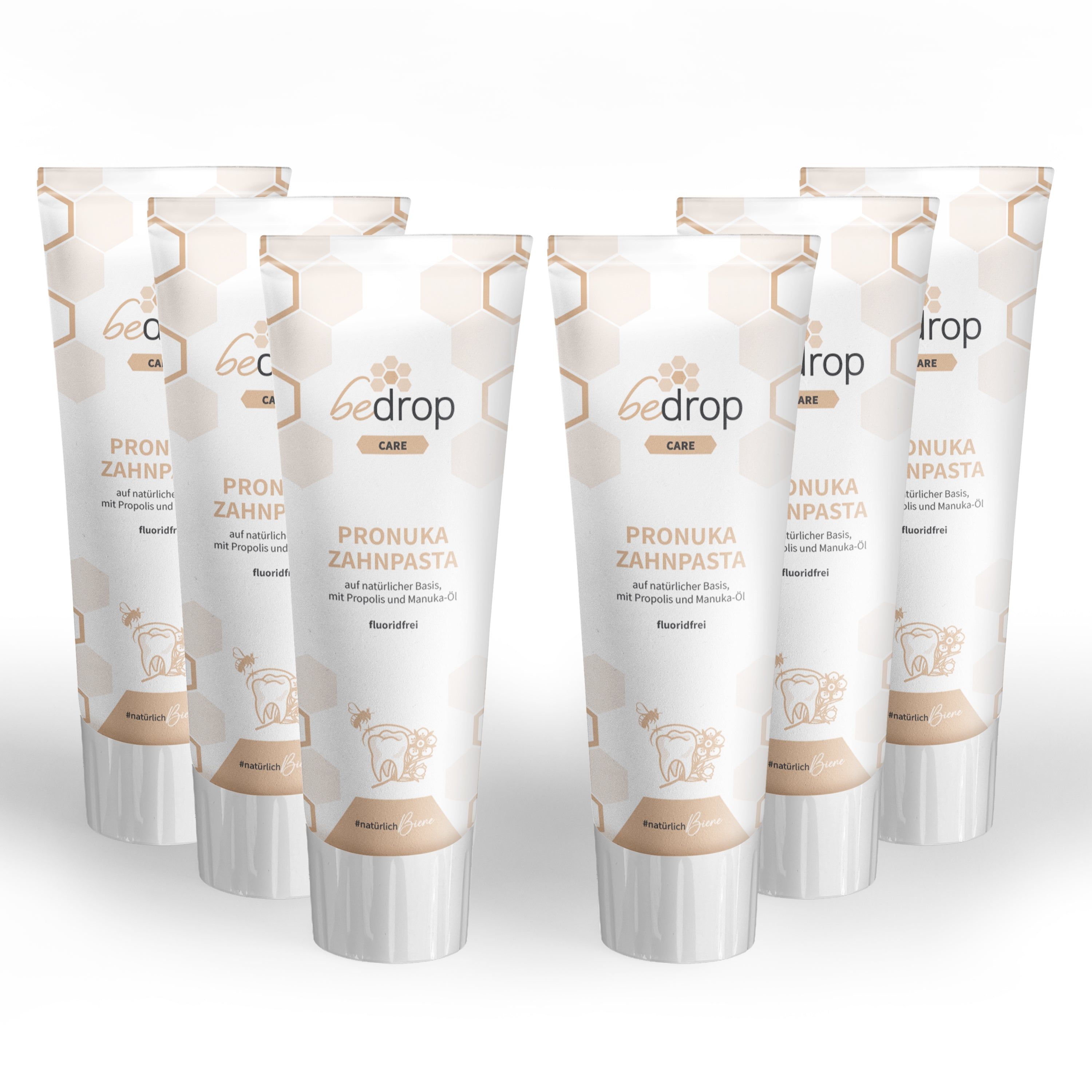 Sechs Tuben bedrop Pronuka Zahnpasta. Weiße Tuben mit braunen Akzenten und Produktinformationen. Aufschrift: Pronuka Zahnpasta, fluoridfrei.