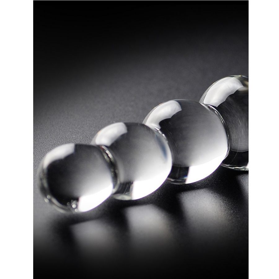 Nahaufnahme von Glasdildo im Kugeldesign. Transparentes Glas, glatte Oberfläche. Schwarzer Hintergrund.