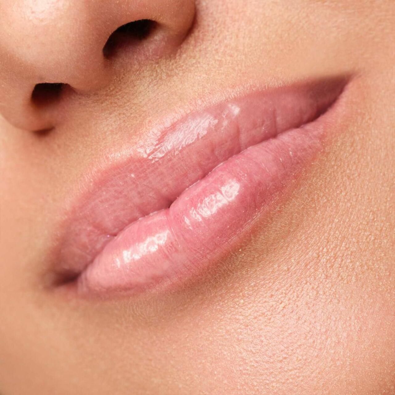 Nahaufnahme von Lippen. Glänzender, rosa Lippenstift auf den Lippen.