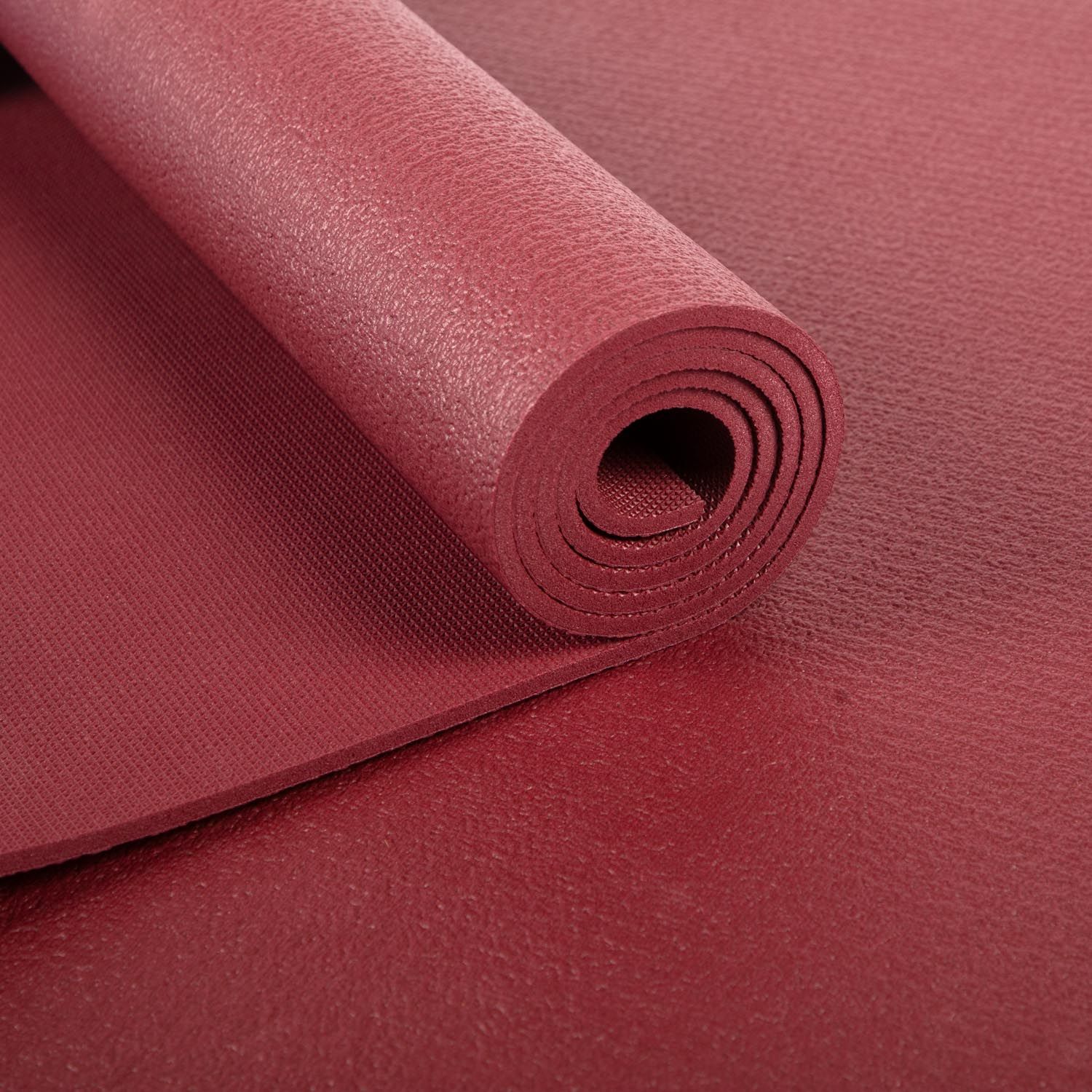 Bordeauxfarbene Yogamatte, aufgerollt. Nahaufnahme der gerollten Oberfläche.