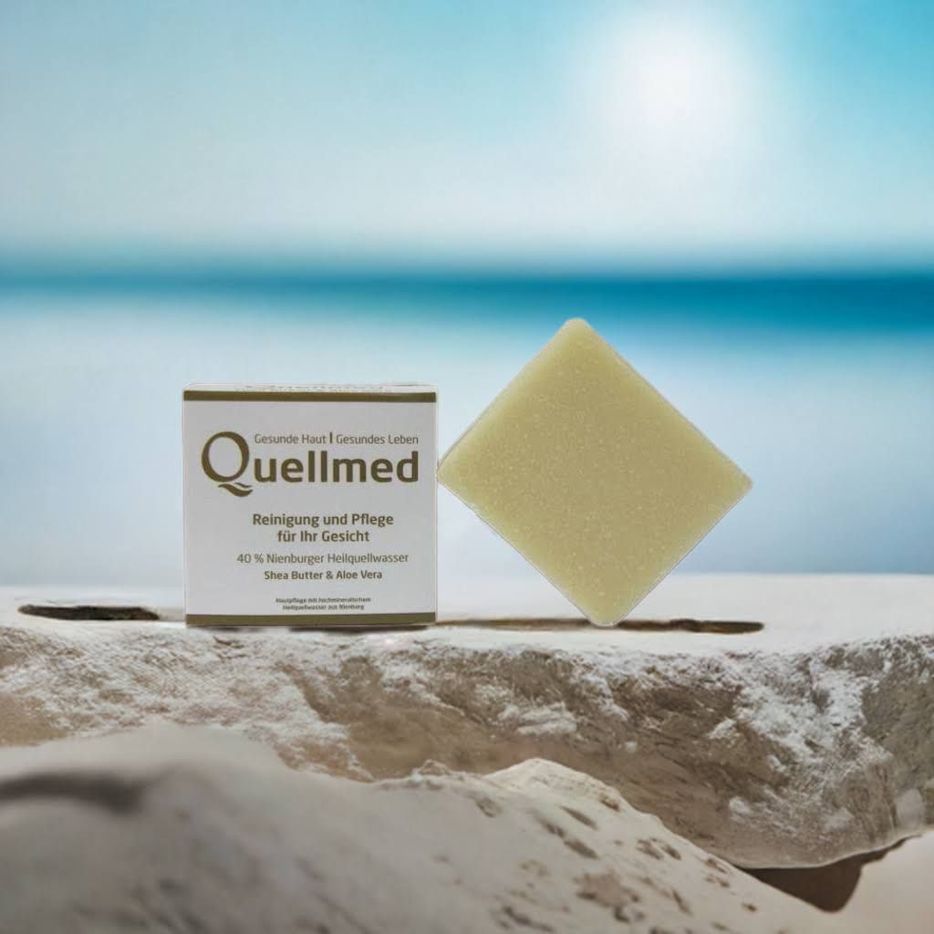 Quellmed-Verpackung und Schwamm auf Stein. Hintergrund: Meer. Produktinformationen: Reinigung & Pflege für Ihr Gesicht, 40% Nienburger Heilquellwasser.