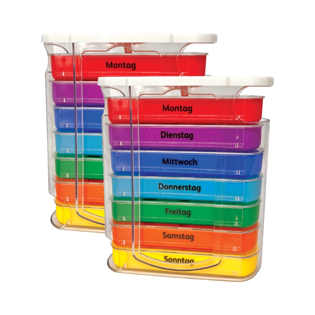 Zwei Tablettenboxen mit farbigen Fächern für die Wochentage. Transparente Halterung mit Beschriftung.