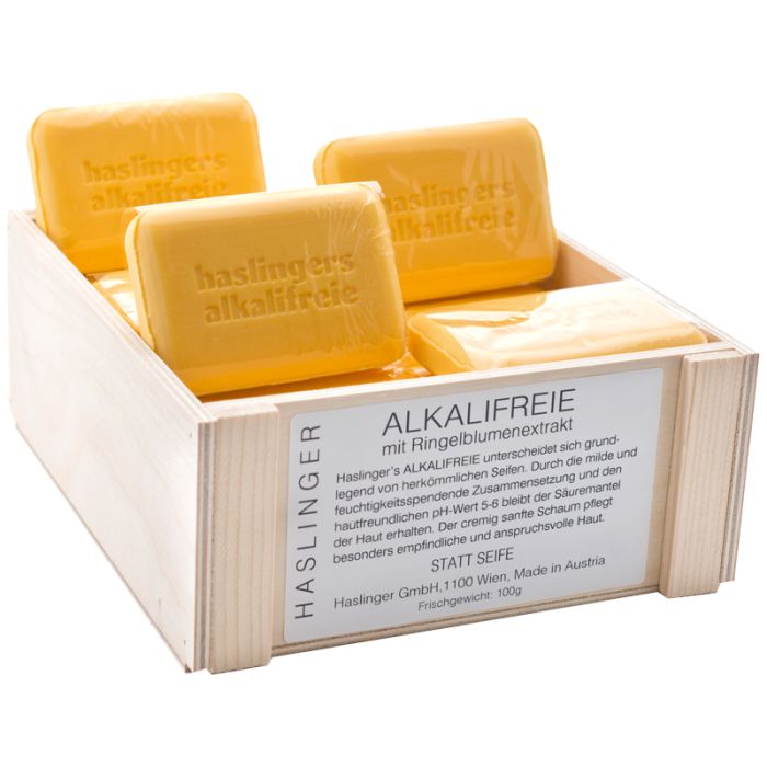 Holzkiste mit gelben Seifenstücken. Aufschrift "haslingers alkalifreie". Etikett mit Produktinformationen.