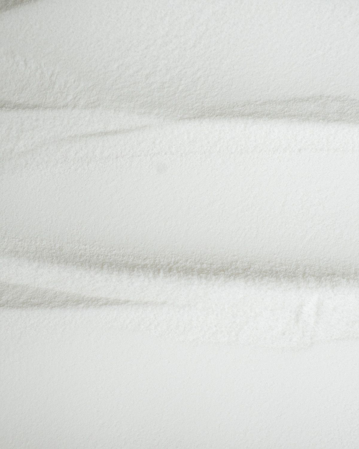 Nahaufnahme der Textur von weißem Pulver mit sanften Wellen.