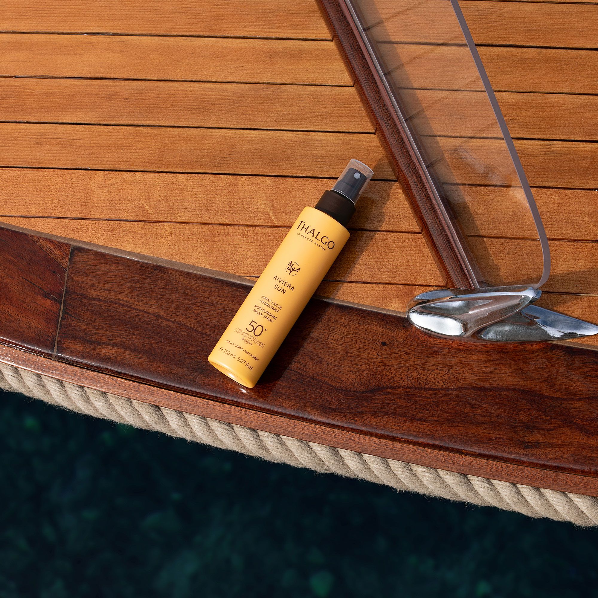 THALGO Sonnenschutz-Spray LSF 50+ auf Holzboot. Gelbe Flasche mit Sprühkopf. Text: Riviera Sun, 50.