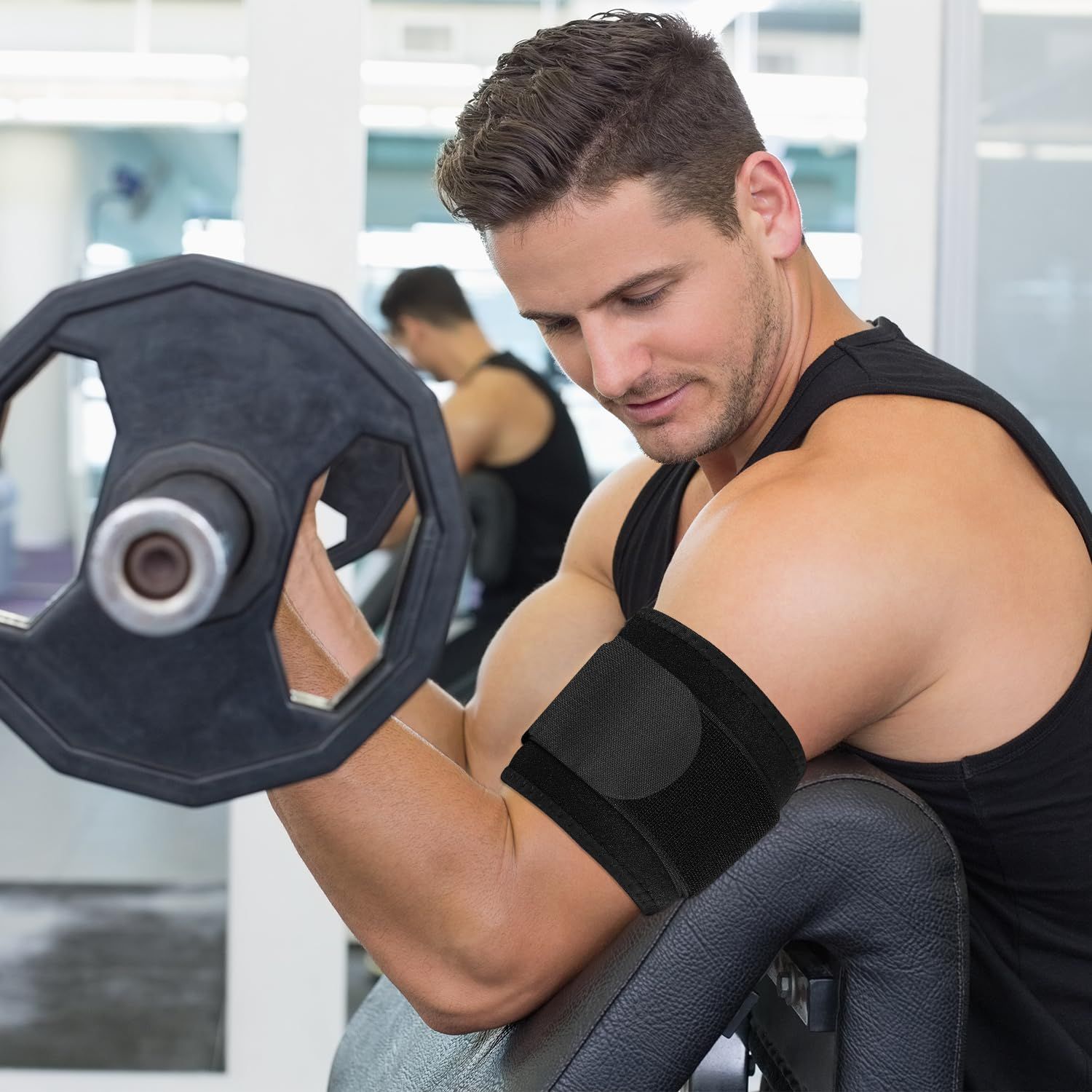 Mann mit Bizeps-Curls im Fitnessstudio, trägt eine schwarze Ellbogenbandage.