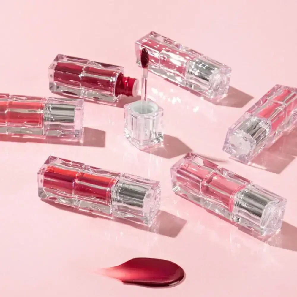 Mehrere TINTIR Waterism Glow Tints mit rotem Gloss-Schlieren und Applikator.