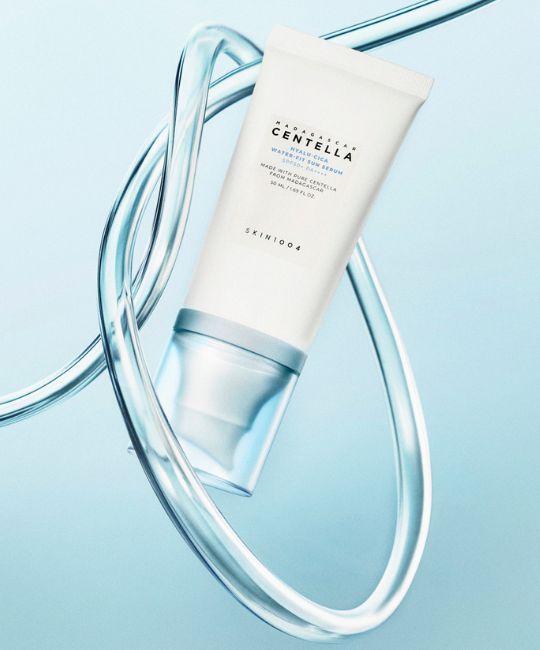 Weiße Tube Madagaskar Centella Hyalu-Cica Water-Fit Sun Serum, umgeben von Wassersträngen.