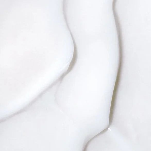 Abstrakte Nahaufnahme von weißer Lotion auf heller Haut.