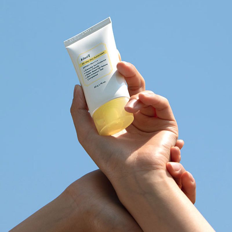 Hände halten eine weiße Tube mit gelbem Deckel. Aufschrift: klairs All-day Airy Sunscreen SPF50+ PA++++. 50 g 1.76 oz.