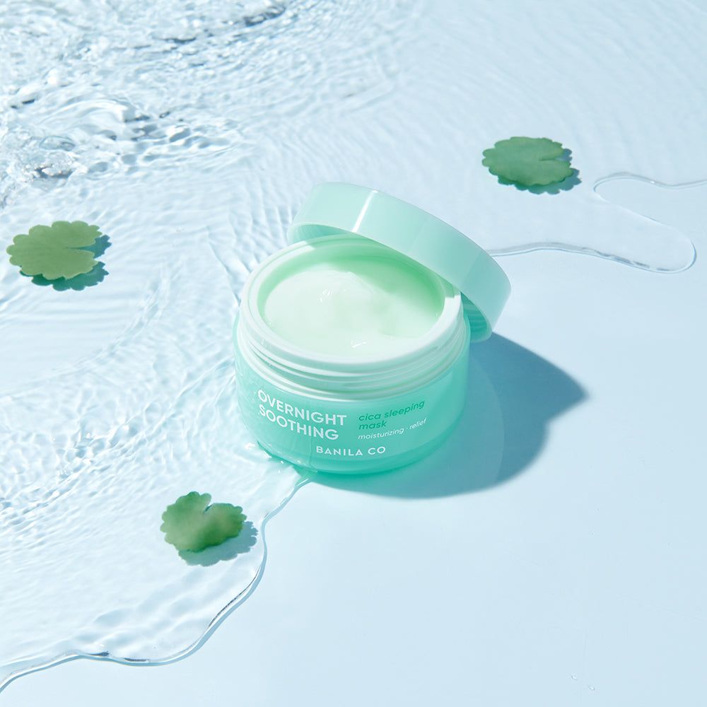 Offener grüner Tiegel im Wasser, umgeben von grünen Blättern. Text: OVERNIGHT SOOTHING, BANILA CO, Cica Sleeping Mask.