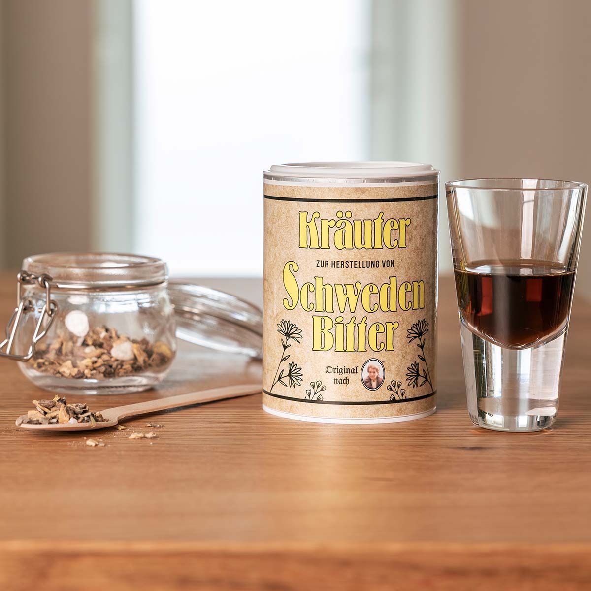 Dose mit gelbem Etikett, Glas mit Kräutern, Shotglas mit Flüssigkeit, Holzlöffel. Aufschrift: Kräuter, Schweden Bitter.