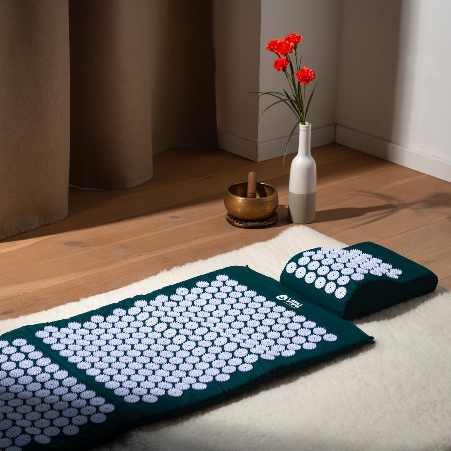 Akupressur-Matte und Kissen, dunkelgrün. Matte und Kissen mit weißen Noppen. Auf weißem Fell.