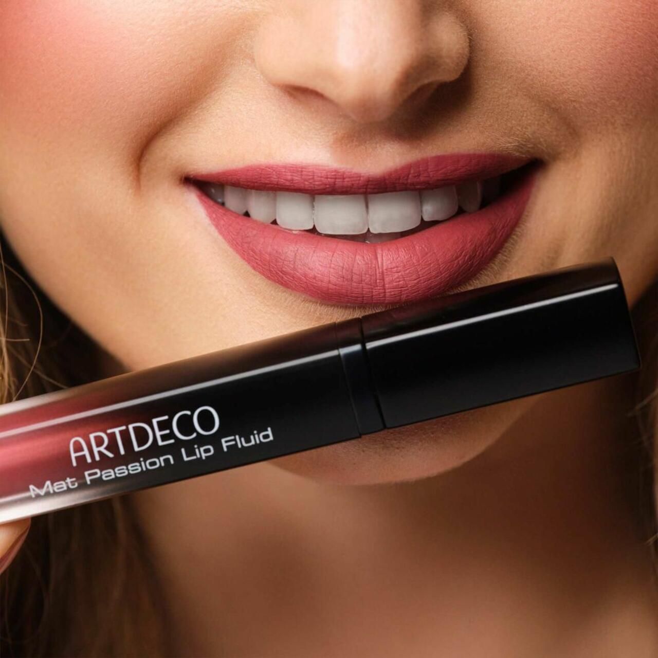 Person hält Artdeco Mat Passion Lip Fluid. Lippen mit Lippenstift. Schwarze Tube mit Produktnamen.