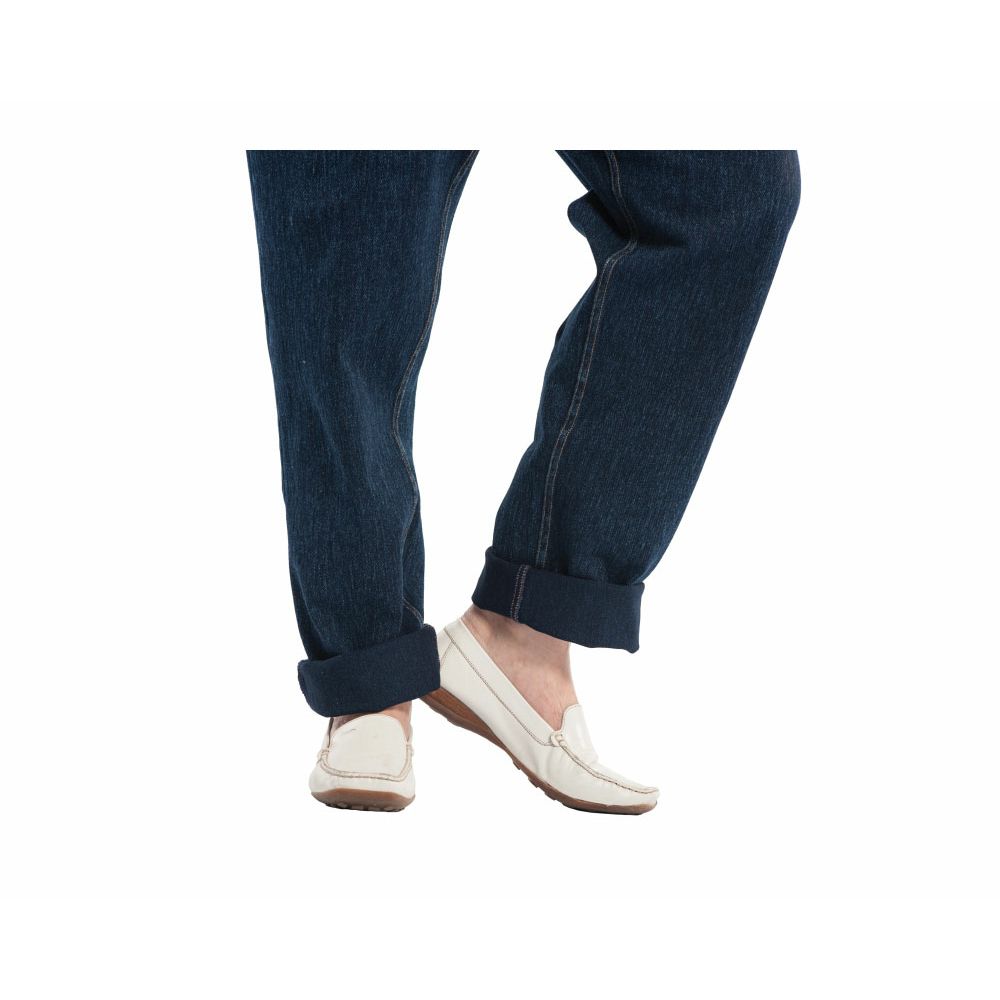 Detailansicht der Jeans CareActive. Dunkelblaue Jeanshose mit umgeschlagenen Säumen. Weiße Schuhe. Nahaufnahme der Füße.