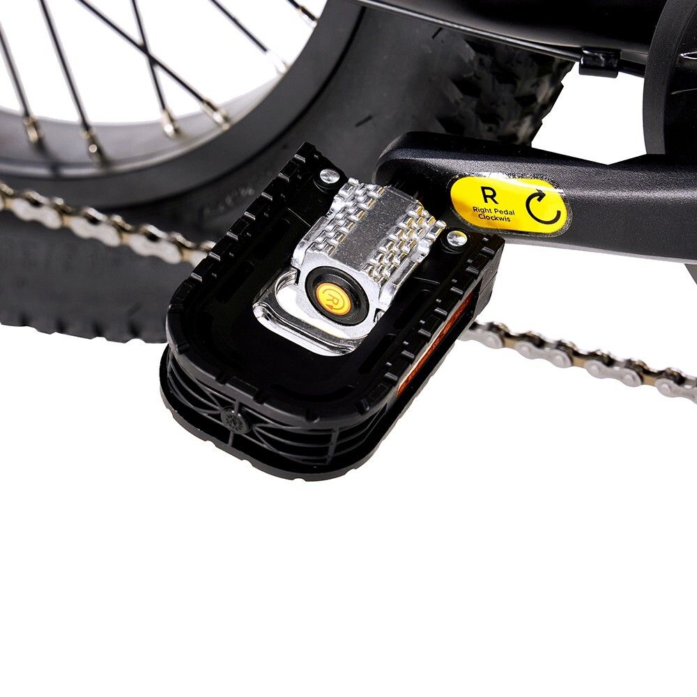 Nahaufnahme eines Pedals eines schwarzen Elektrofahrrads. Sichtbar: Pedal, Reflektor, gelber Aufkleber.