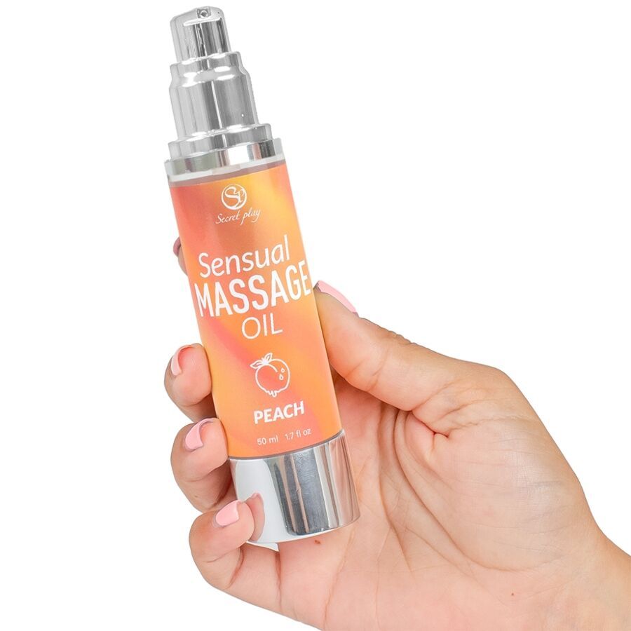 Flasche mit Massageöl, gehalten von einer Hand. Aufschrift: Sensual Massage Oil Peach. Silberner Pumpkopf.
