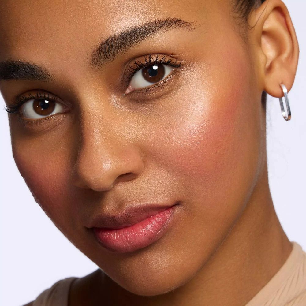 Porträt einer Frau mit Rouge auf den Wangen. Sie trägt Ohrringe. Helles Make-up.