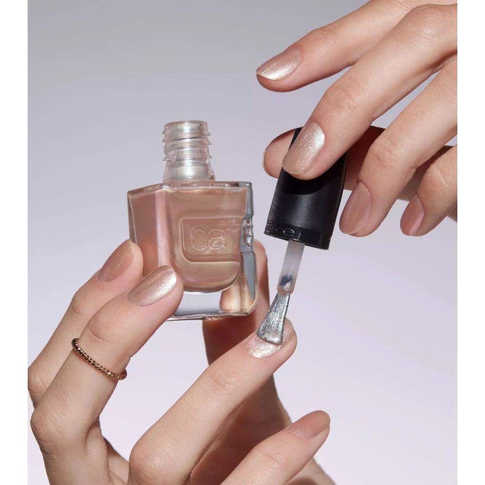 Hände lackieren einen Fingernagel mit einem rosa Nagellack. Der Markenname Catrice ist auf der Flasche sichtbar.