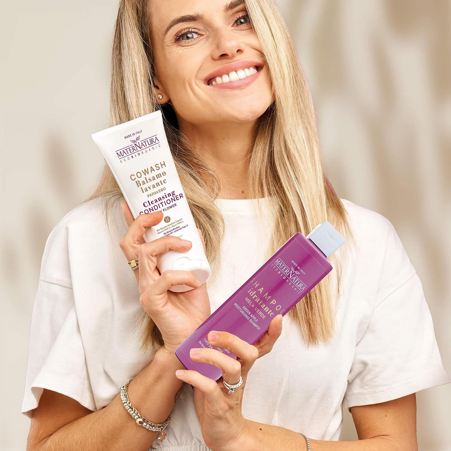 Frau hält eine weiße Tube MaterNatura Cowash und eine lila Flasche MaterNatura Shampoo.