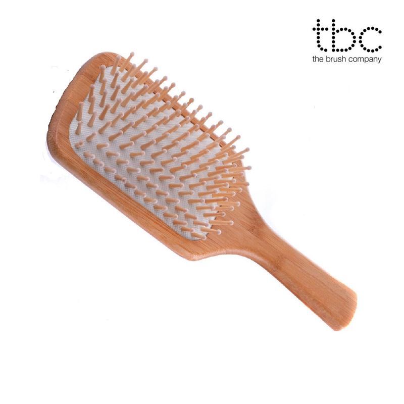 Holz-Haarbürste mit Logo 'tbc the brush company', rechteckiger Kopf, Holzzinken auf weißem Kissen.