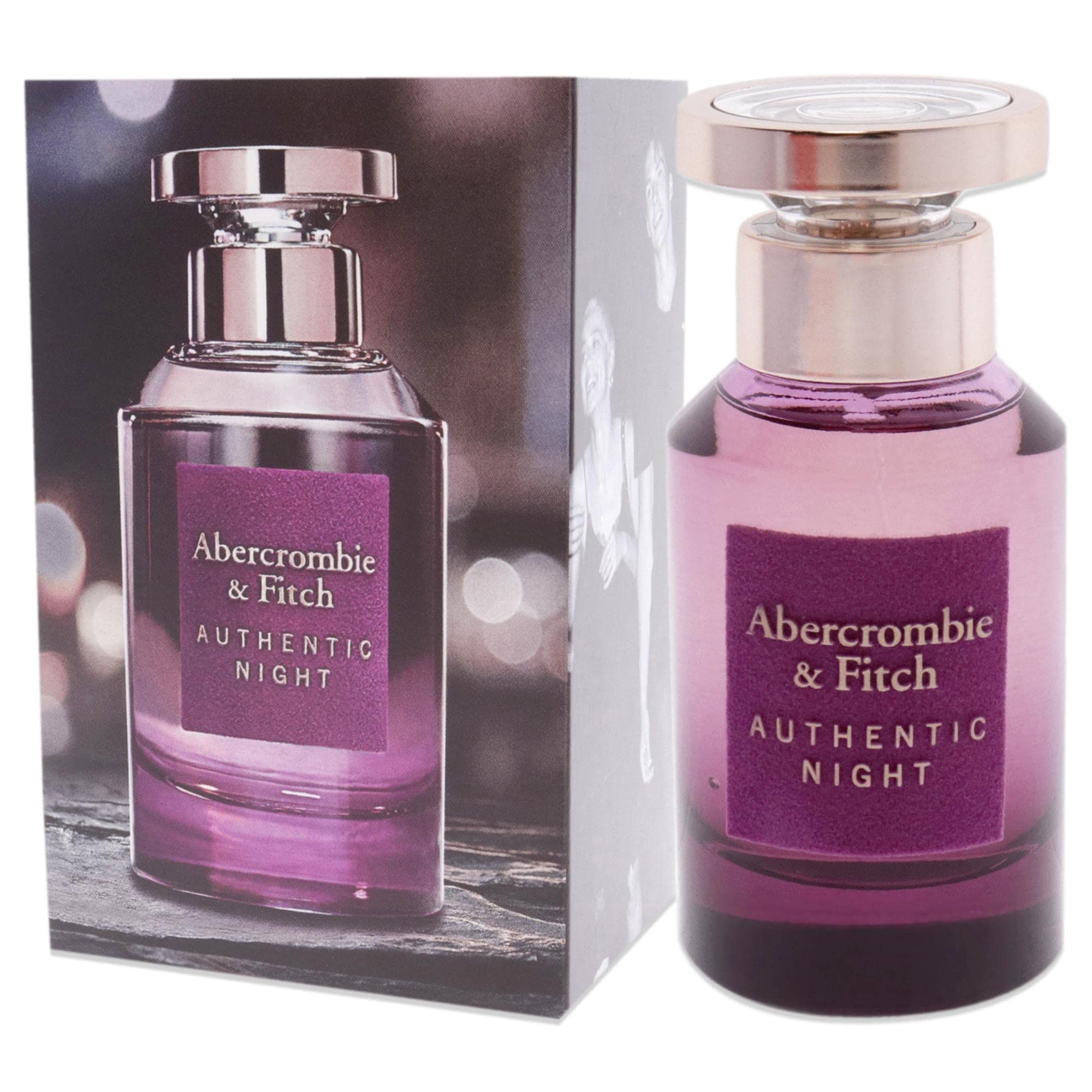 Abercrombie & Fitch Authentic Night Flakon und Schachtel. Flakon mit rosafarbenem Inhalt, goldfarbenem Verschluss und lila Etikett. Schachtel mit Bild.