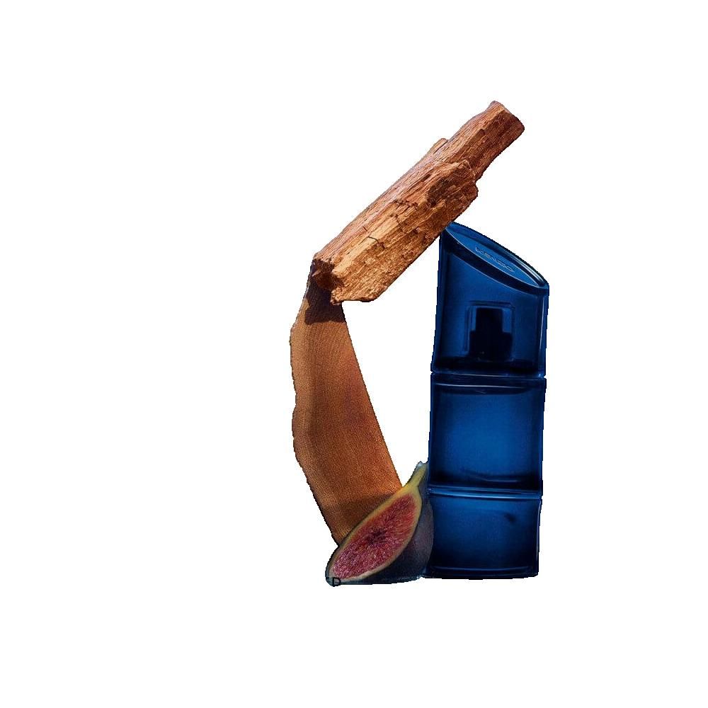 Blaues Parfumflakon, Holzstück, Feige. Flakon mit dunklem Zerstäuber. Holz und Feige neben dem Flakon.