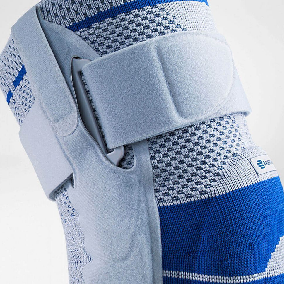 Blaue und weiße Kniebandage mit Klettverschlüssen. Das Produkt ist am Bein einer Person angebracht.