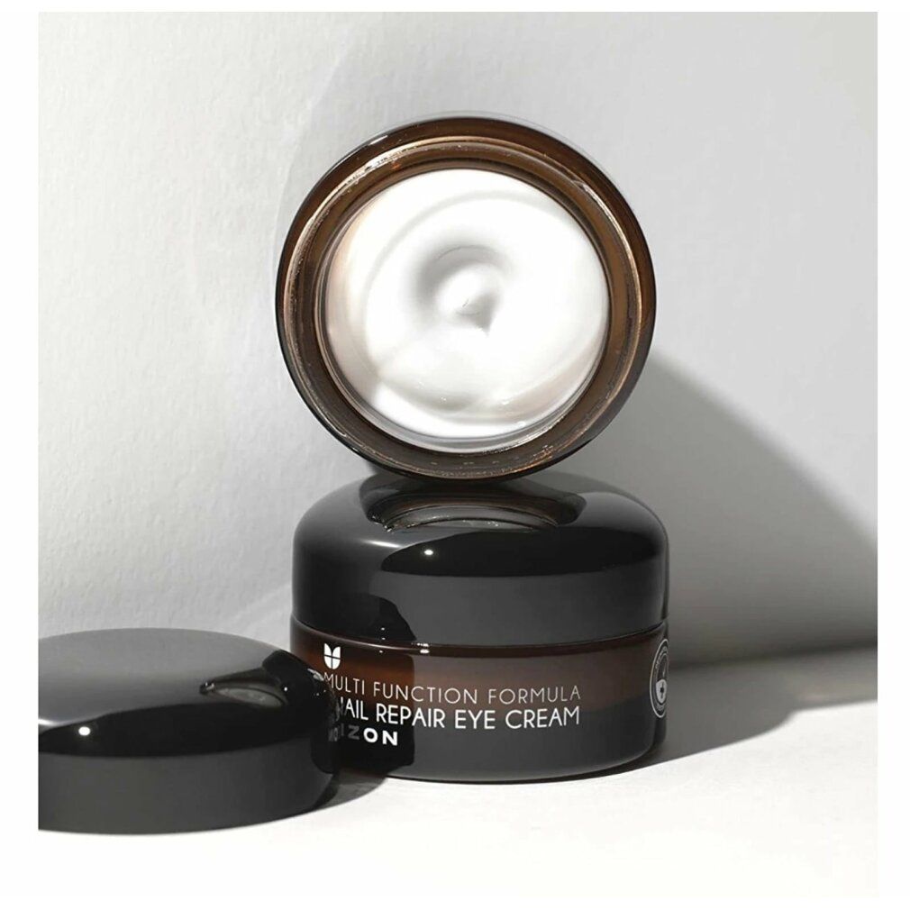 Geöffnete braune Glasdose mit schwarzem Deckel. Creme sichtbar. Aufschrift: Multi Function Formula Snail Repair Eye Cream MIZON.