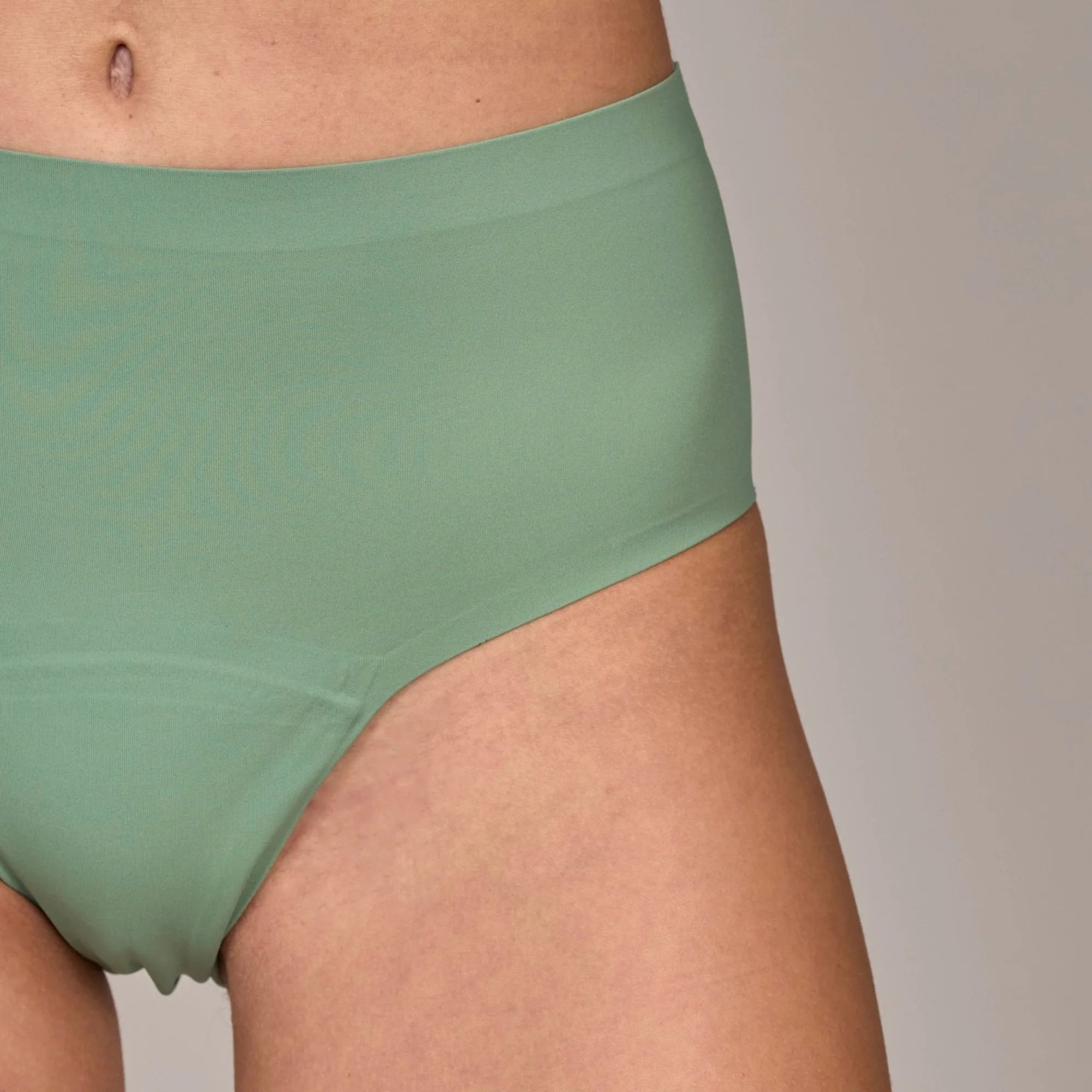 Detailaufnahme einer hellgrünen, nahtlosen, auslaufsicheren Unterhose. Hoher Bund, bedeckt den Bauch. Angedeuteter Schritt.