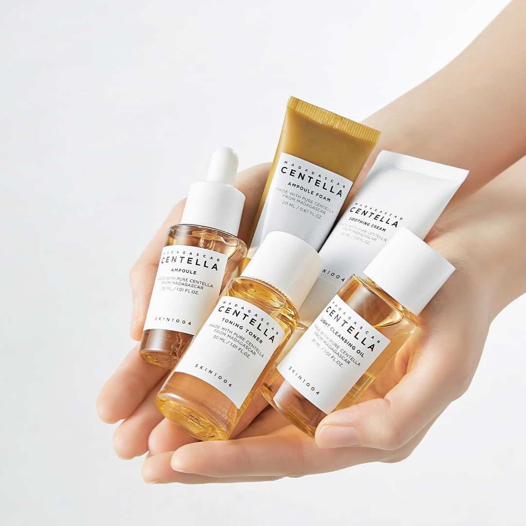 Hände halten das SKIN1004 Madagascar Centella Travel Kit mit Ampoule Foam, Light Cleansing Oil, Toning Toner, Ampoule und Soothing Cream.