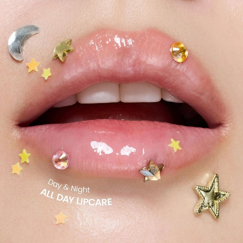 Nahaufnahme von Lippen mit Glanz. Dekorationen: Sterne, Mond und Schmucksteine.