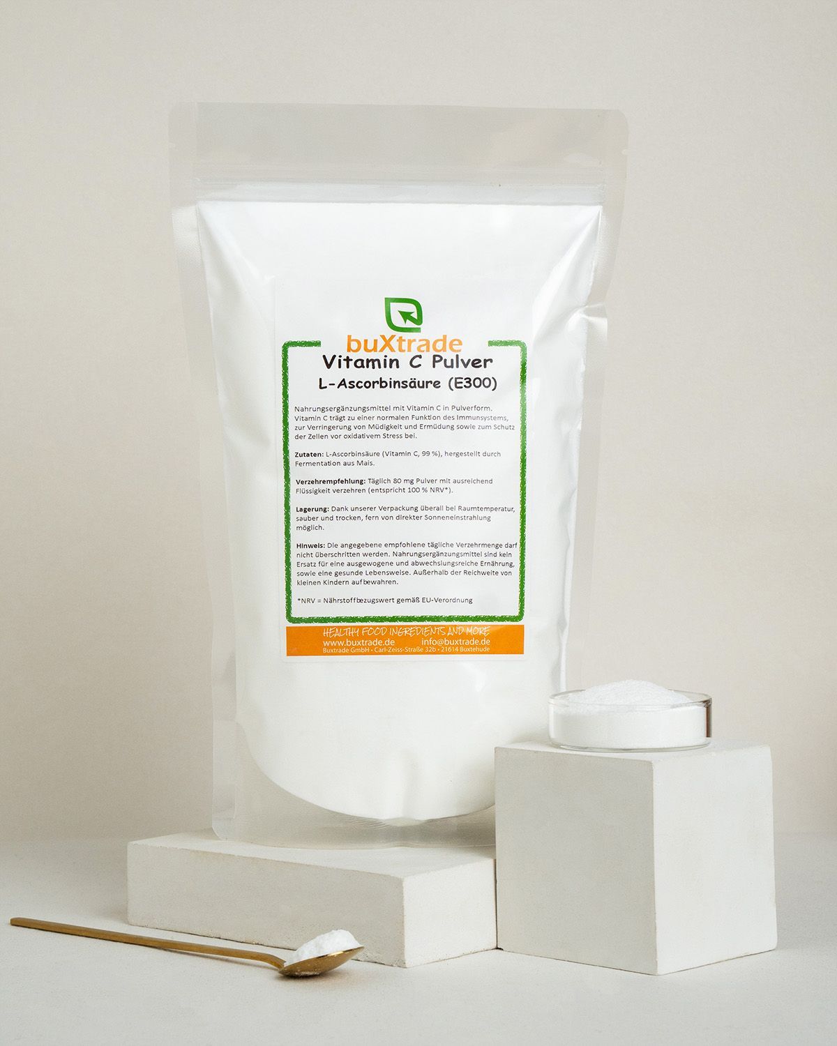 buxtrade Vitamin C Pulver mit Glas, Löffel und Verpackung auf Podesten.