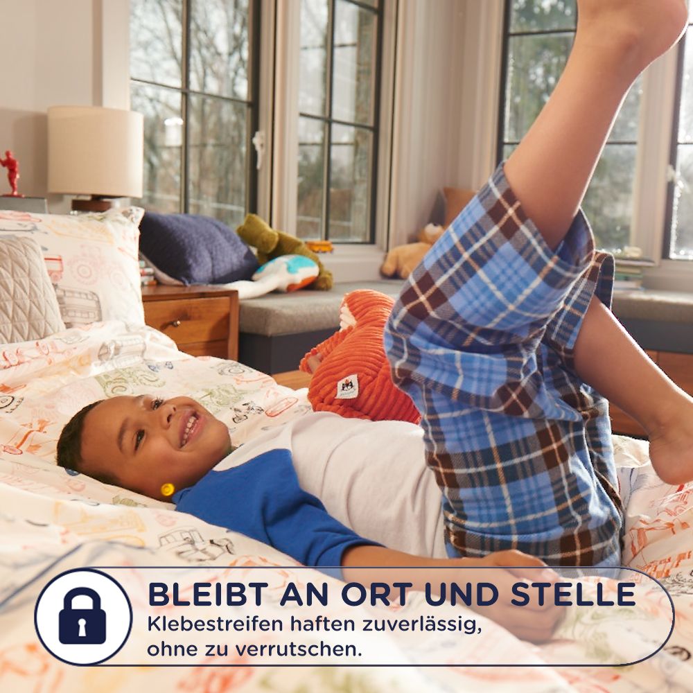 Kind liegt auf einem Bett. Text: Bleibt an Ort und Stelle. Klebestreifen haften zuverlässig, ohne zu verrutschen.