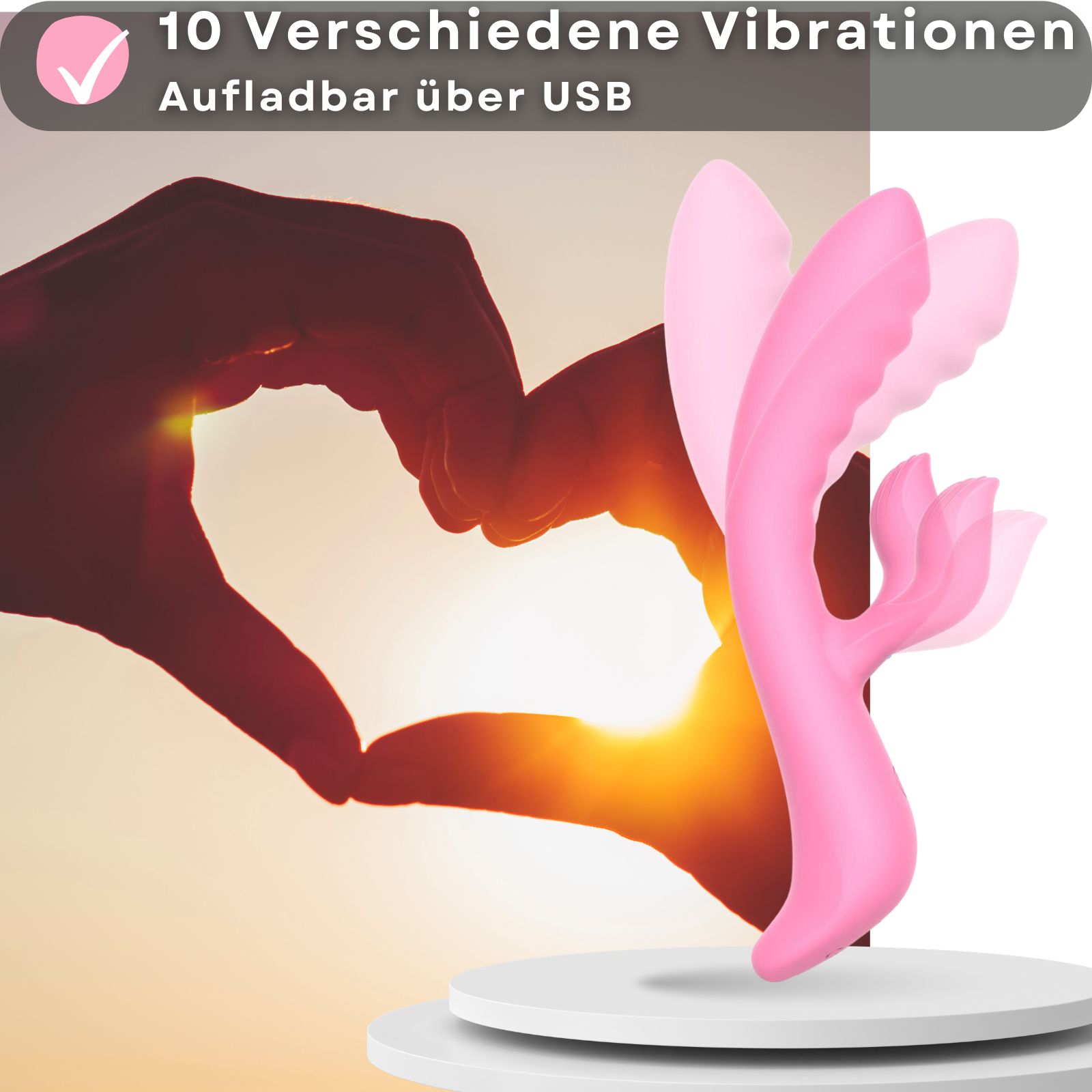 Rosa Vibrator. 21cm lang, 3,5cm Durchmesser. Auf Podest. USB-aufladbar. 10 Vibrationsmodi. Hintergrund: Hände.