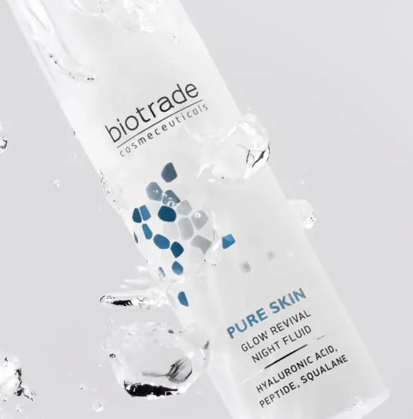 Weißes Fläschchen mit Pumpe und transparentem Deckel. Aufschrift: Biotrade, Pure Skin Glow Revival Night Fluid. Wasser umgibt das Produkt.